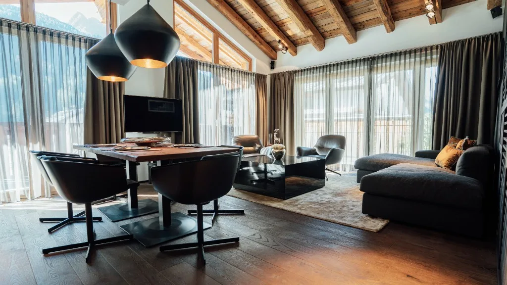 Open-plan living and dining area with timber-beamed ceiling, dining table and sofa landscape