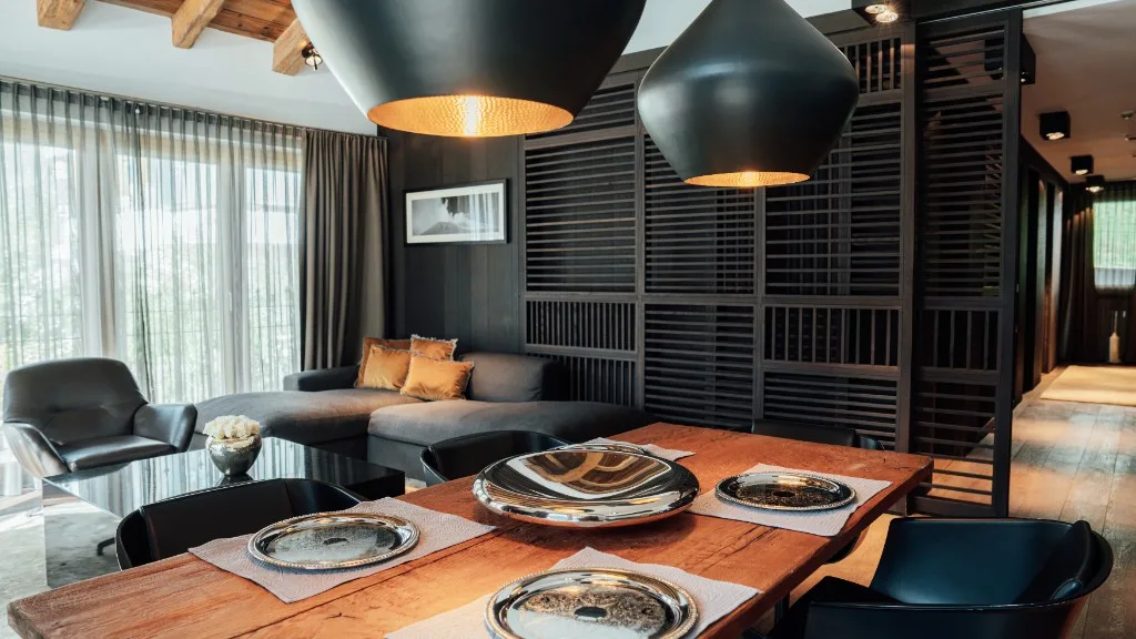 Laid dining table of reclaimed wood with silver plates and black pendant lights