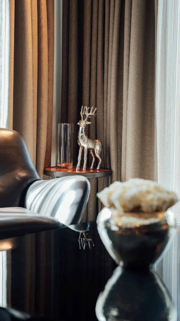 Side table with a silver stag figurine by the window