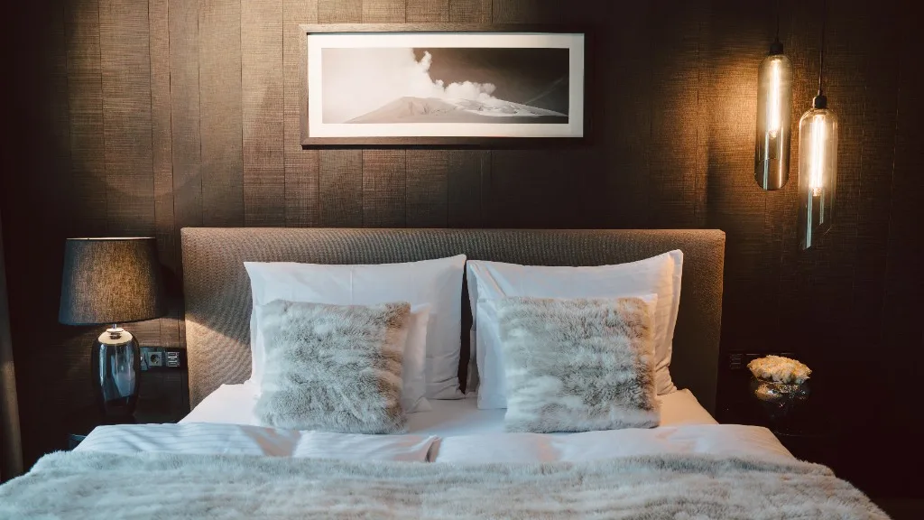 King-size bed with fur cushions, bedside lamp and black-and-white picture