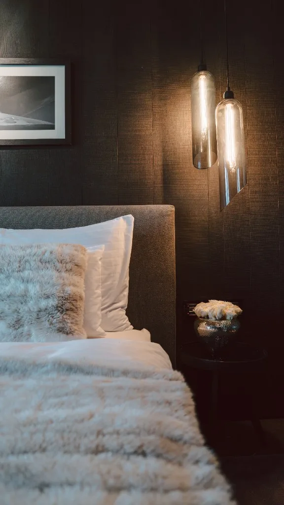 Bed detail with fur cushions and glass pendant lights