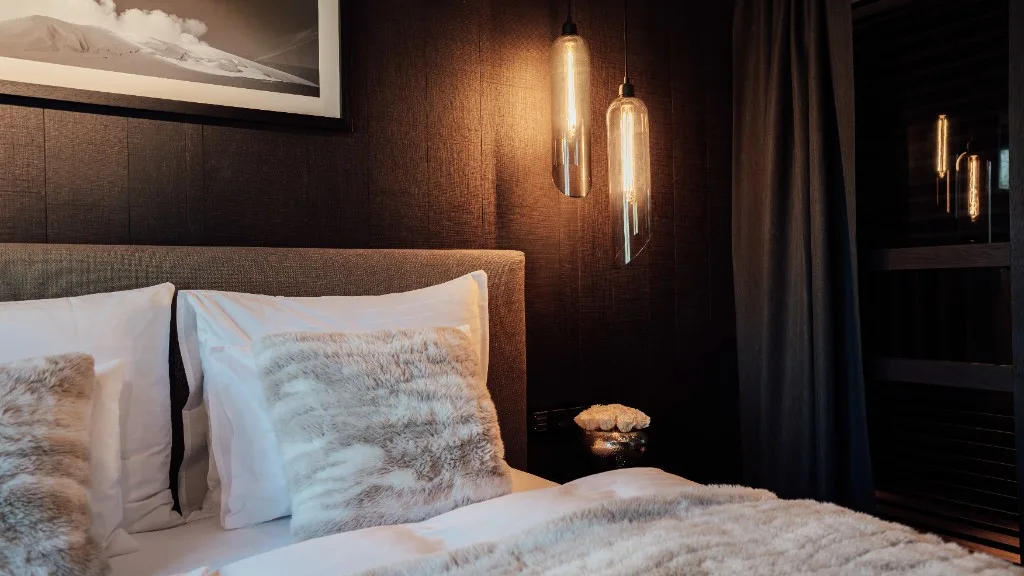 Headboard of the bed with fur cushions and warmly glowing pendant lights