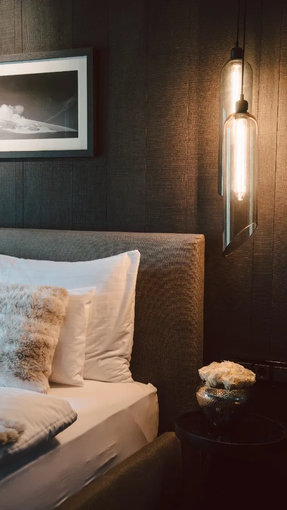 Bed detail with pendant light and roses on the bedside table